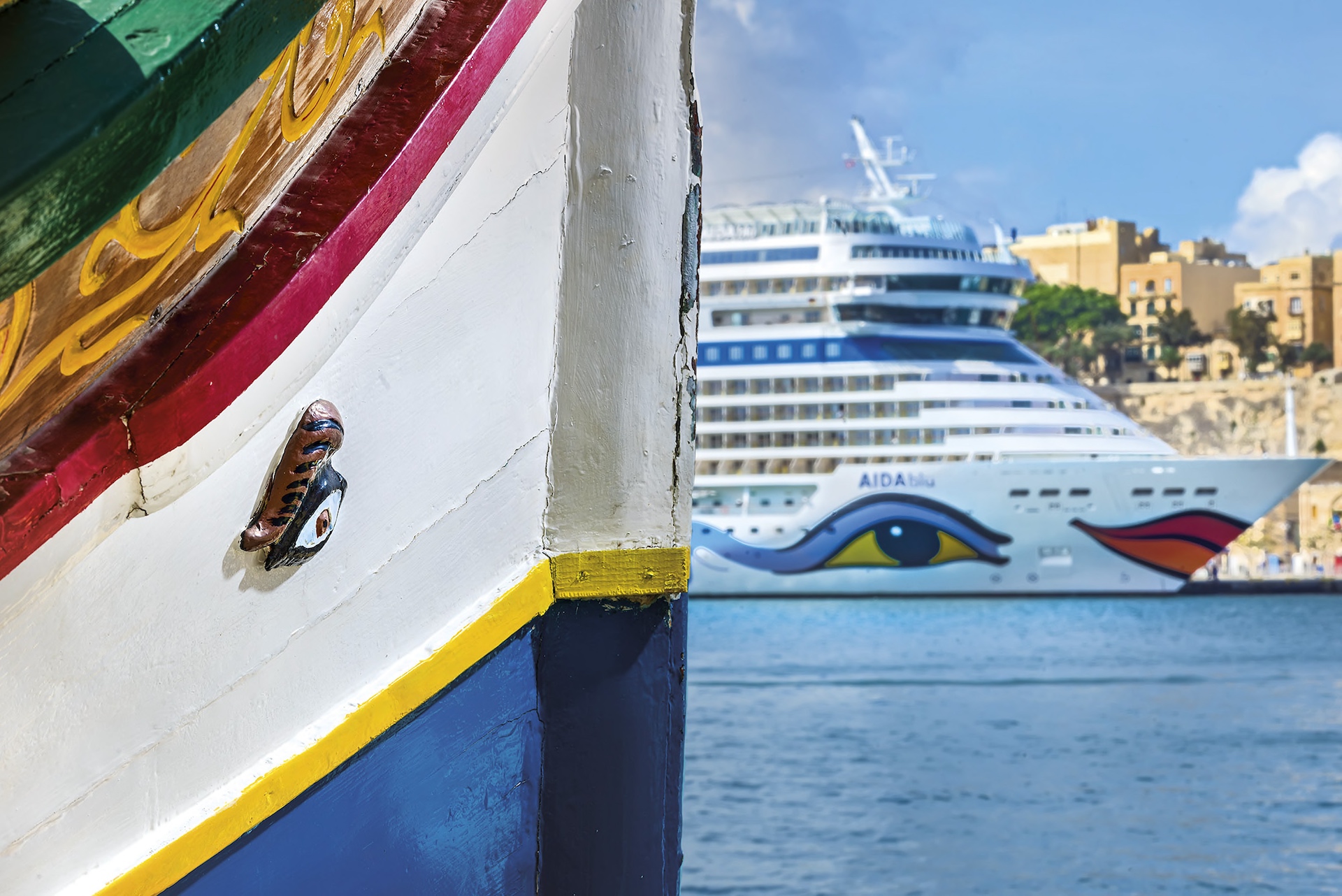 A traditionnal Maltese luzzu sporting the eye of osiris, with a cruise liner in the background