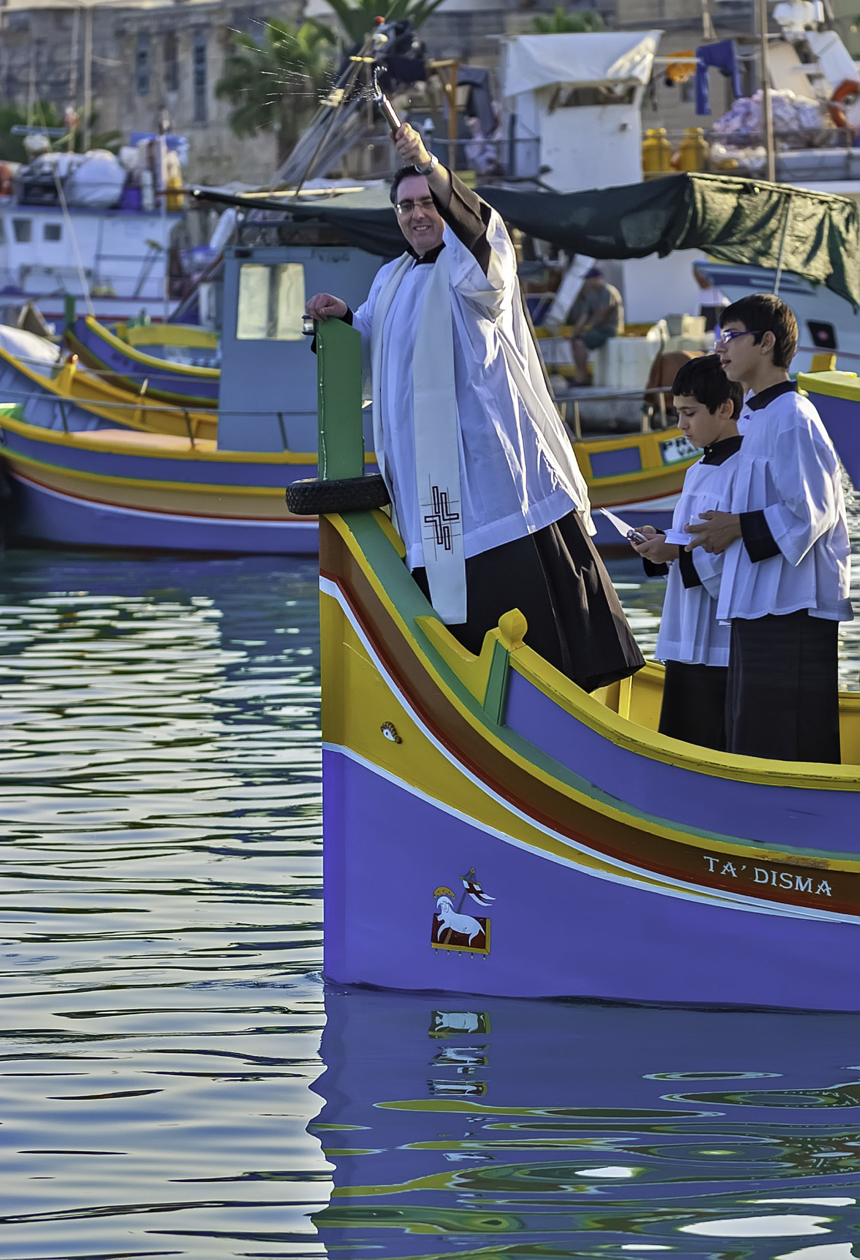 the parish priest blesses the fishermen and their boats with holy water, wishing them safe and bountiful catches, before the lampuki season